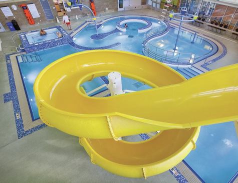 The facility features a combination recreation pool, spa and sauna. Its bright yellow, towering figure-eight water slide is a colorful form among the surrounding blue and white hues. When the slide isn’t 

being used, its exit alcove provides a 

convenient place for private swim lessons. 